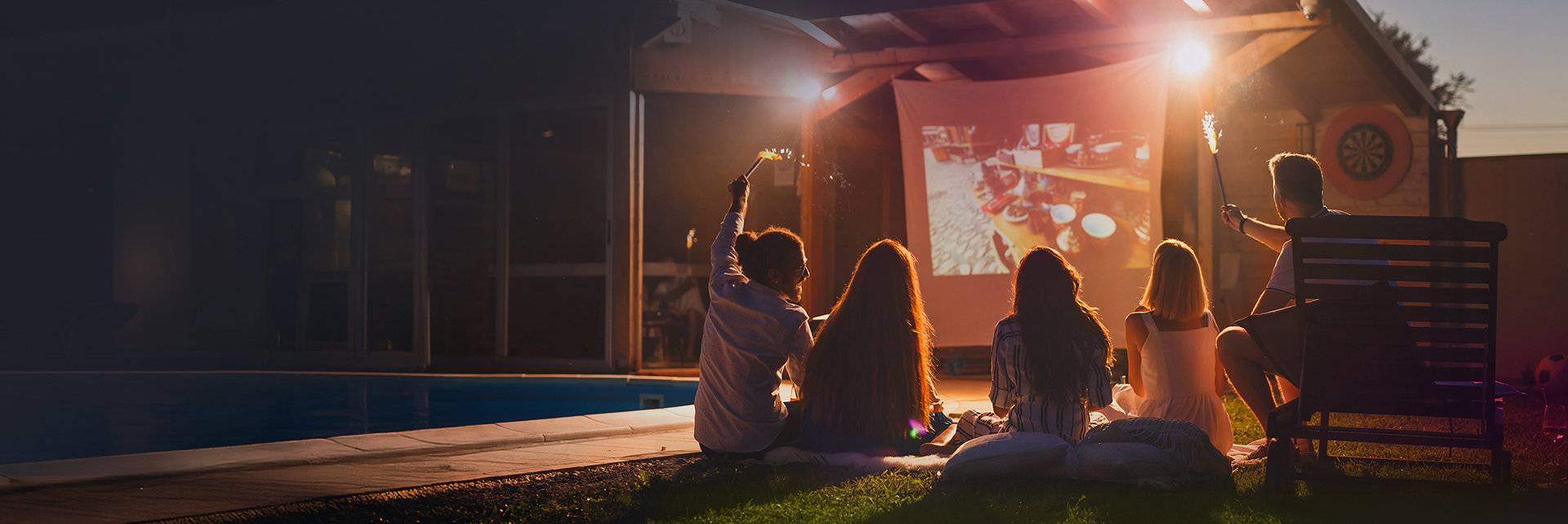 outdoor cinema, projector screen, poolside, group of people, fireworks sparkler